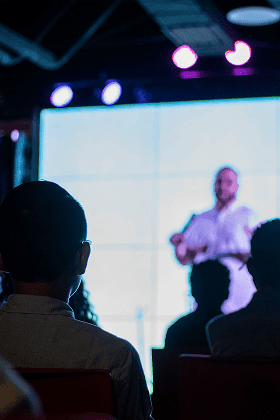 Several silhouetted people listening to a speaker, showing the engaging atmosphere at Open Strategising.