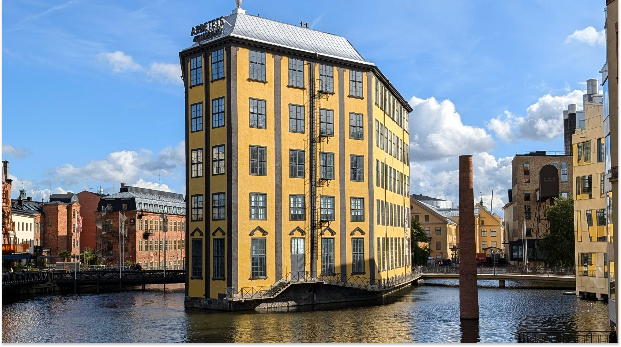 Gul historisk industribyggnad vid vattnet i Norrköping